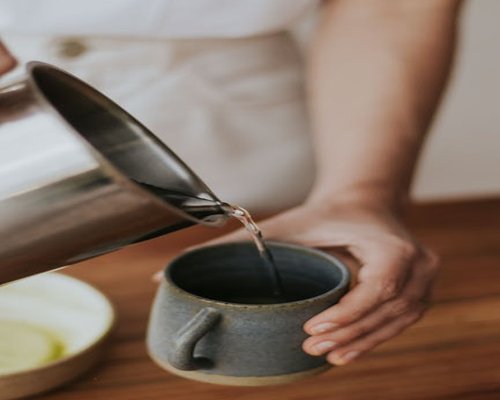 Person pouring hot water to make tea in the morning